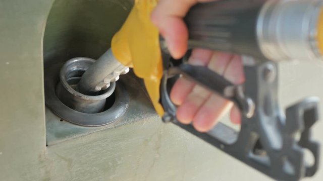 Green military car refuels with gasoline at gas station