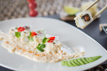 Traditional rolls with fish and rice on a white plate with sauce and wasabi. Japanese food.