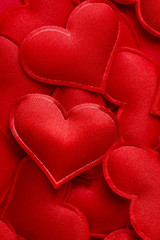 Background of red hearts.Top view of red satin hearts. Texture of red satin. Close-up, vertical, top view. Valentine's day concept.