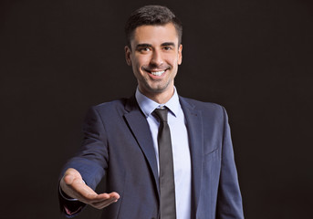 Young businessman holding something on dark background