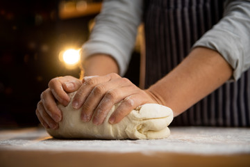 Obraz na płótnie Canvas Extreme close up of female chef kneading dough for a delicious pizza