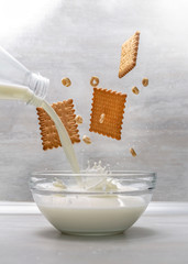pouring milk into a bowl with biscuits and cornflakes 