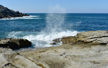 Seascape with waves breaking against the rocks and blue sky. Galicia, Spain.