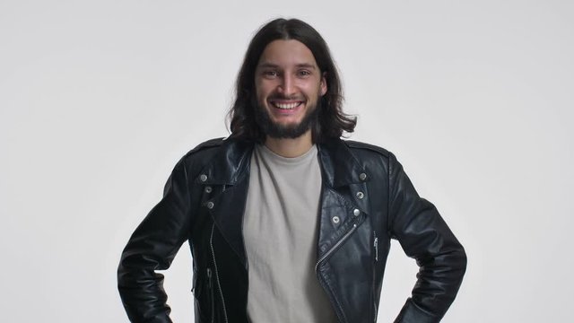 An attractive young man with long hair in a black leather jacket is nodding his head positively isolated over white background