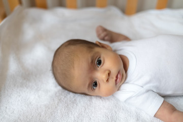 Newborn baby. A little boy in white clothes. Beautiful portrait of a toddler. Big-eyed baby.