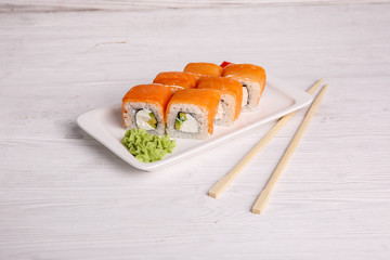 rolls with salmon, cream cheese and avacado, restaurant menu on a light wooden background