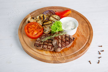 Grilled beef steak served on a wooden Board with fried vegetables