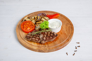 Grilled beef steak served on a wooden Board with fried vegetables