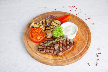 Grilled beef steak served on a wooden Board with fried vegetables
