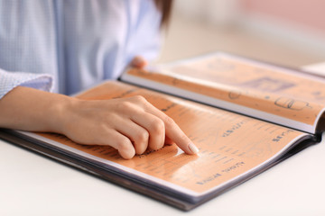 Young woman with menu sitting in restaurant, closeup