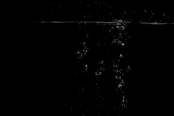 something falls into the water and causes seething and air bubbles on a black background for installation