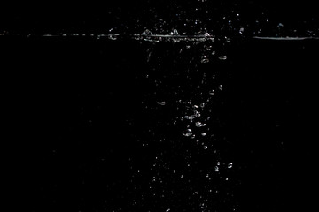 something falls into the water and causes seething and air bubbles on a black background for installation