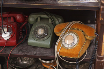 Multicolored antique vintage analog phones dialed. dusty and dirty, swivel, scrolling phone on a wooden shelf of an antique counter