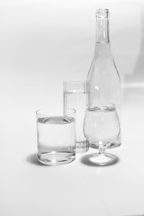 Transparent glass set of glasses of different shapes with a bottle isolated on a white background. Three filled glasses of water.