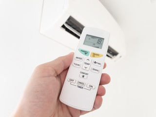 Modern airconditioner unit with a hand holding a remote.