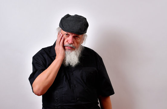 Old man in a thoughtful mood.Senior gentleman in a reflective mood.Elderly man in a pensive mood.. .Mature gentleman with a newsboy cap and black guayabera shirt and long white beard..