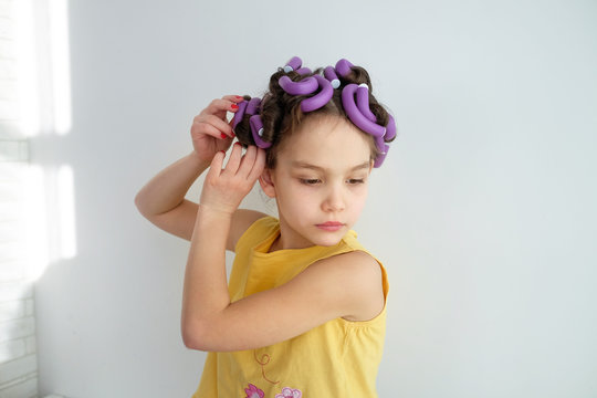 a little girl pretends to be an adult woman or her mommy with curlers in her hair. The concept of kids pretending to be adults.