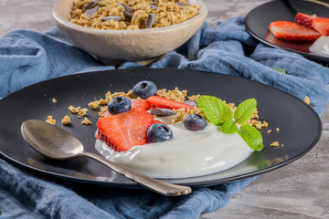 Ripe blueberries and strawberries with yogurt and granola