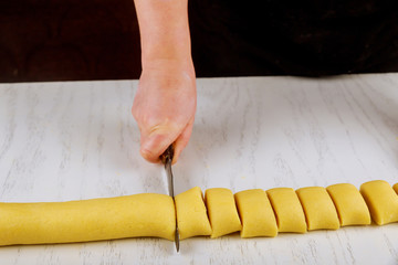 Chef cuts dough with a knife in equal portion for cooking biscuits.