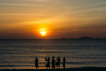 Fototapeta premium Colorful dawn, sunset on a calm sea, sunrise. Beautiful sea background. A charming start to the day. Silhouette of a group of people on a background of the sea