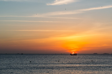 Colorful dawn, sunset on a calm sea. Silhouette of a fishing boat on the horizon.  Beautiful sea background, landscape. Fiery colors.