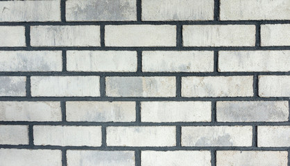 The texture of the facing bricks is white with a rough black grout for mocap. Photo of a wall lined with white bricks in the loft style. Light background in grunge style.