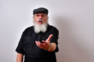 Old man flipping a gold coin .Elderly gentleman flipping gold coin for luck.Senior man flipping a coin .. .Mature gentleman with a newsboy cap and black guayabera shirt and long white beard..