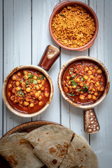 Indian garbanzo beans curry served in clay pots on white wooden background