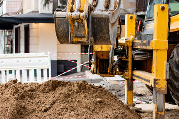 Road works and crawler excavator digging bucket.  Yellow excavator working in the residential area. Heavy excavator during road construction works.