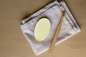 Linen dish cloth, sopa and bamboo toothbrush on wooden table. Top view. 