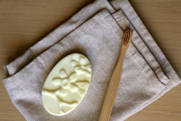 Linen dish cloth, sopa and bamboo toothbrush on wooden table. Top view. 