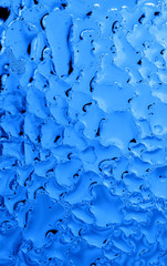 Blue drops of water on glass as an abstract background