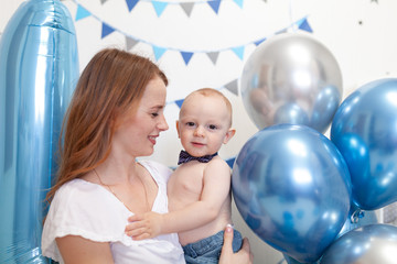 Portrait of happy mother and baby on the background of birthday decorations