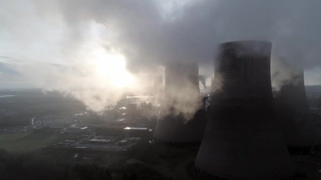 Aerial view of UK power station cooling towers, Sunrise glowing through smoke steam emissions