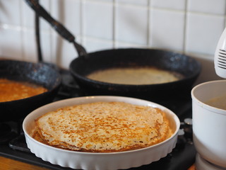 Spring, we meet Maslenitsa. Seeing off winter. Cooking pancakes on a gas stove. Next to the dough and ready-made pancakes.