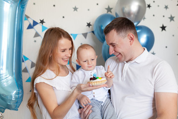 Portrait of happy mother, father and baby on the background of birthday decorationss