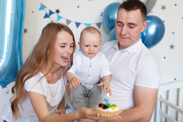 Portrait of happy mother, father and baby on the background of birthday decorationss
