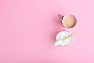 The collagen in the glass, spoon and coffee with milk on a pink background.