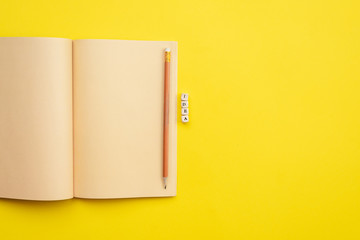 Open empty diary with a pencil and an  inscription idea on yellow background