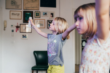 Two Female children holding a joystick playing videogame at home