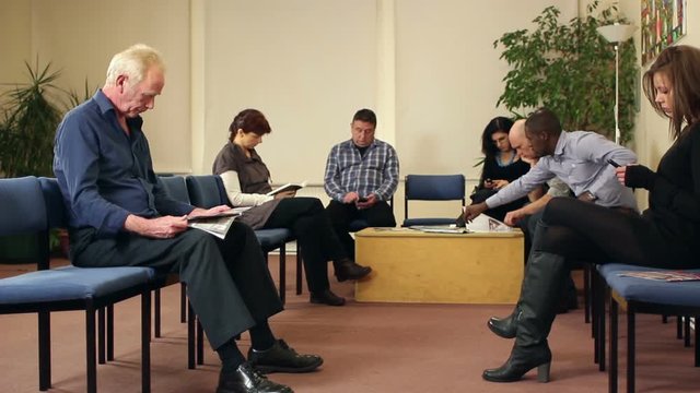 Patients sat in Medical Waiting room awaiting Healthcare appointments. Could be a Doctor or dentist surgery clinic. Stock Video Clip Footage. Tracking Shot