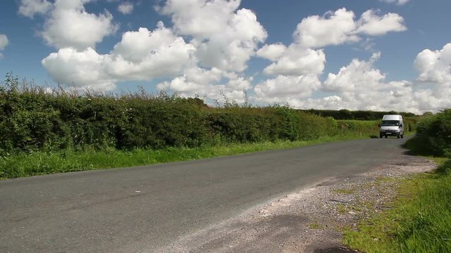 Silver Van drives through the countryside on a road in the summer. Blue sjy and fluffy clouds. Stock Video Clip Footage
