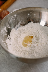 Broken egg with yolk in a bowl with flour. The recipe for the dough