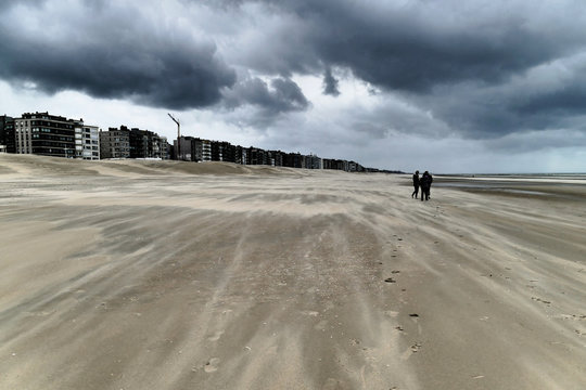 People are walking on the beach during a hurricane-like storm in Koksijde, Flanders, Belgium, Europe