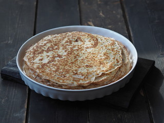 Spring, we meet Maslenitsa. Seeing off winter. Cooking pancakes on a gas stove. Next to the dough and ready-made pancakes.