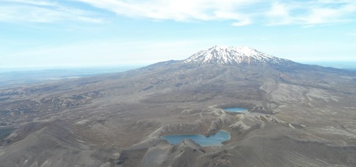 Scenic view of the awesome landscape with the snow capped volcano, moon landscape, blue lakes and dry area of the National Park Tongariro. Beautiful Clouds in the blue sky.