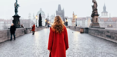 Foto op Plexiglas Karelsbrug Vrouwelijke toerist die alleen op de Karelsbrug loopt tijdens de vroege ochtend in Praag, de hoofdstad van Tsjechië