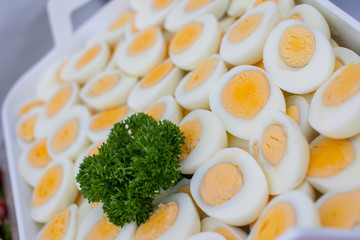 A whole bunch of sliced hard boiled eggs decorated with parsley on a buffet on a festive setting