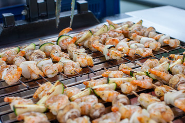 Outdoor picnic scene of seafood bbq with delicious shrimp on skews and prawn spits on a grill 