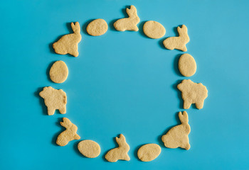 Easter composition. The wreath is made of homemade cookies in the form of Easter bunnies, eggs and lambs on a light blue background.